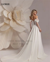 Woman in a white wedding dress standing next to a large floral sculpture with 'LORIE' branding.