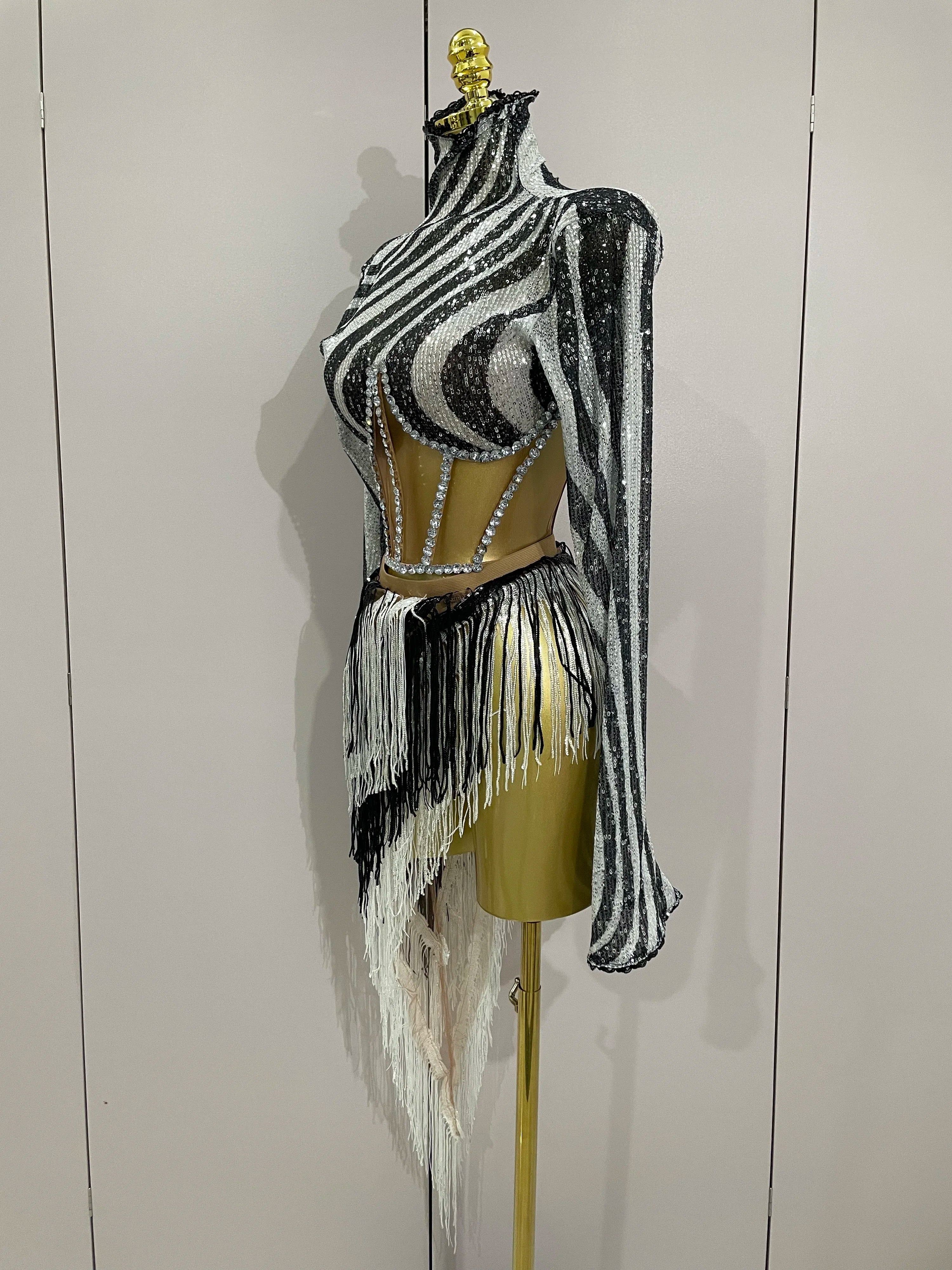 Black and white striped outfit with fringe on a mannequin against a plain background