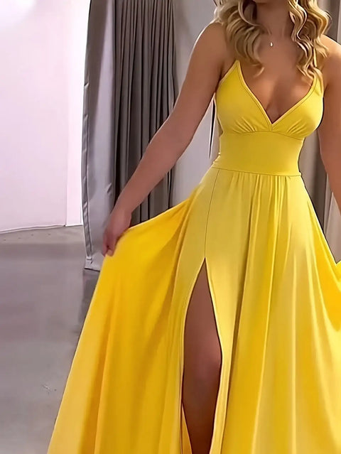 Woman wearing a yellow evening gown with a slit, standing indoors.