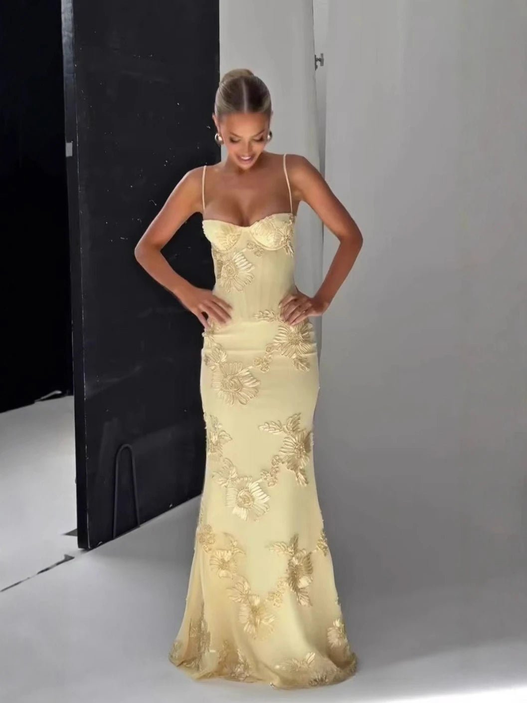 Woman in a light yellow evening gown posing against a gray background