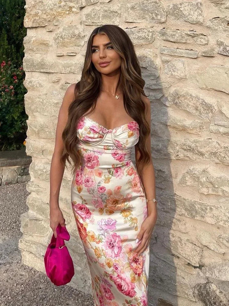 Woman in a floral dress standing against a stone wall