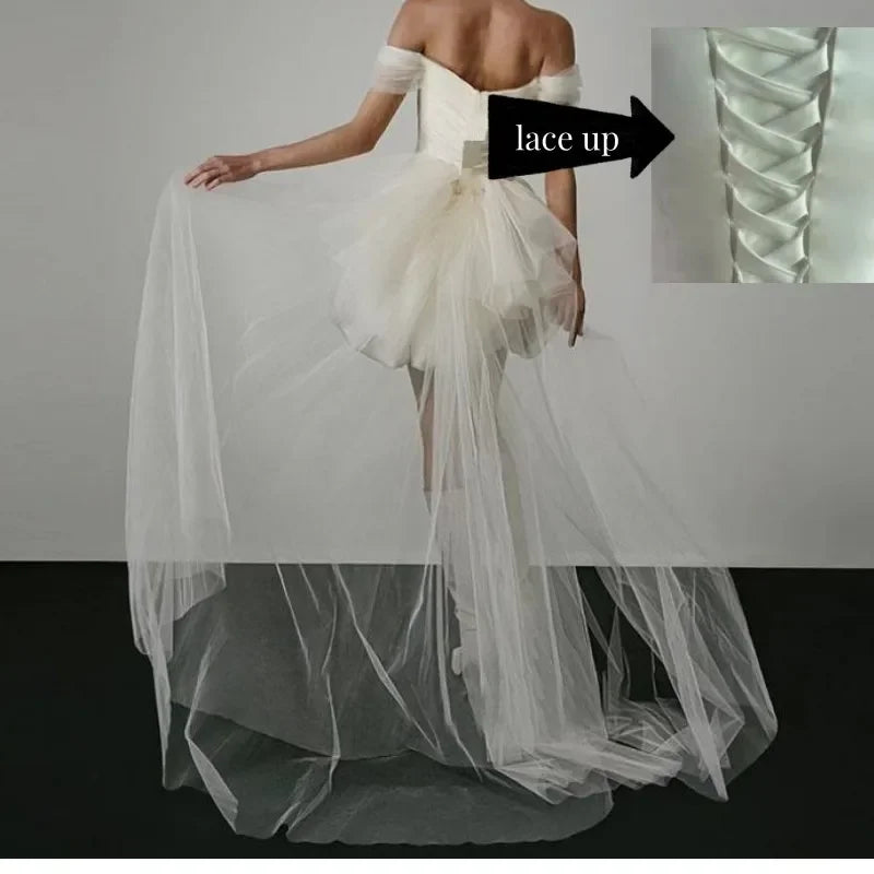 White wedding dress with a sheer overlay on a gray background