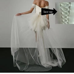 White wedding dress with a sheer overlay on a gray background