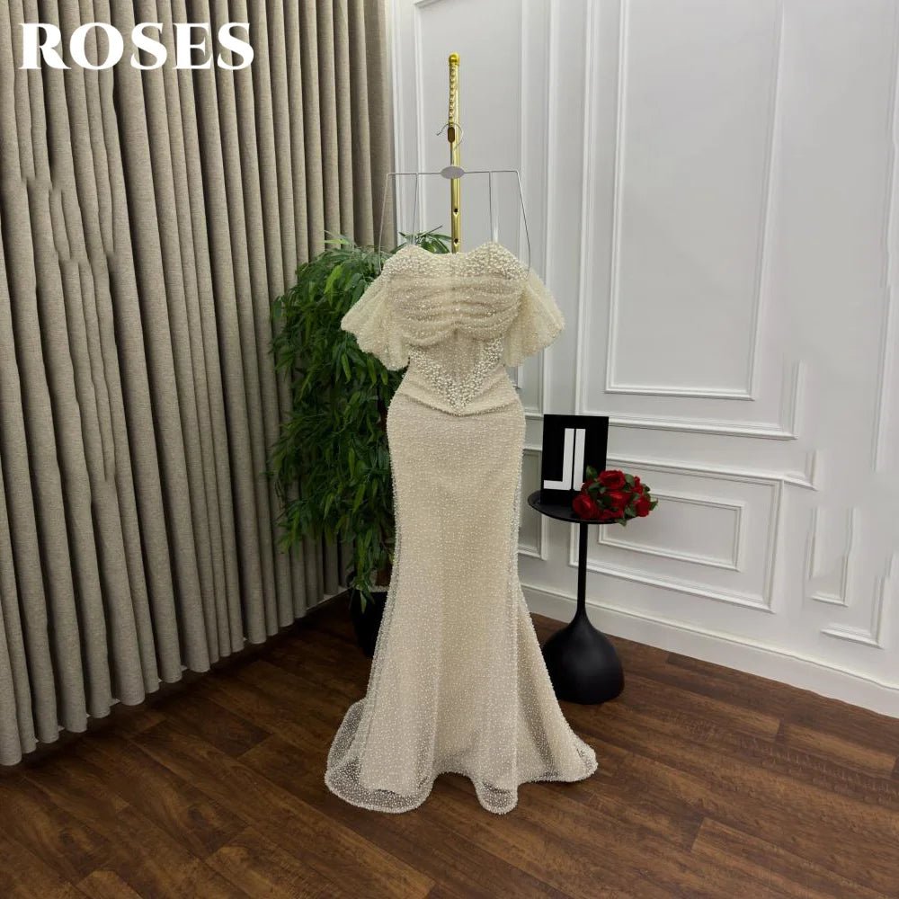 Beige evening gown on a mannequin against a white wall with 'ROSES' branding.