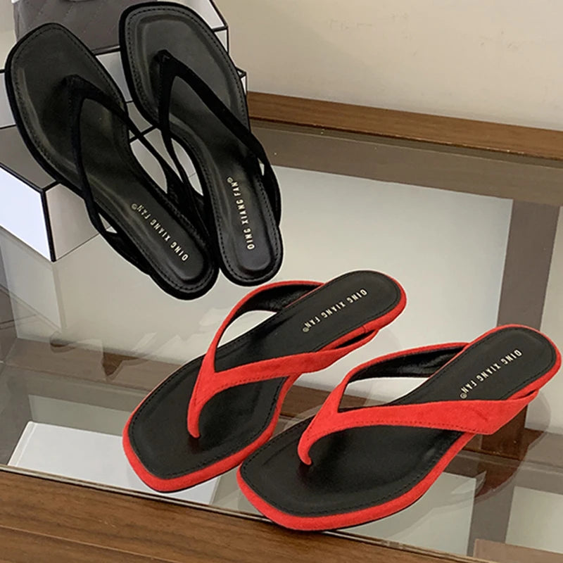 Black and red flip-flops on a glass surface with a neutral background