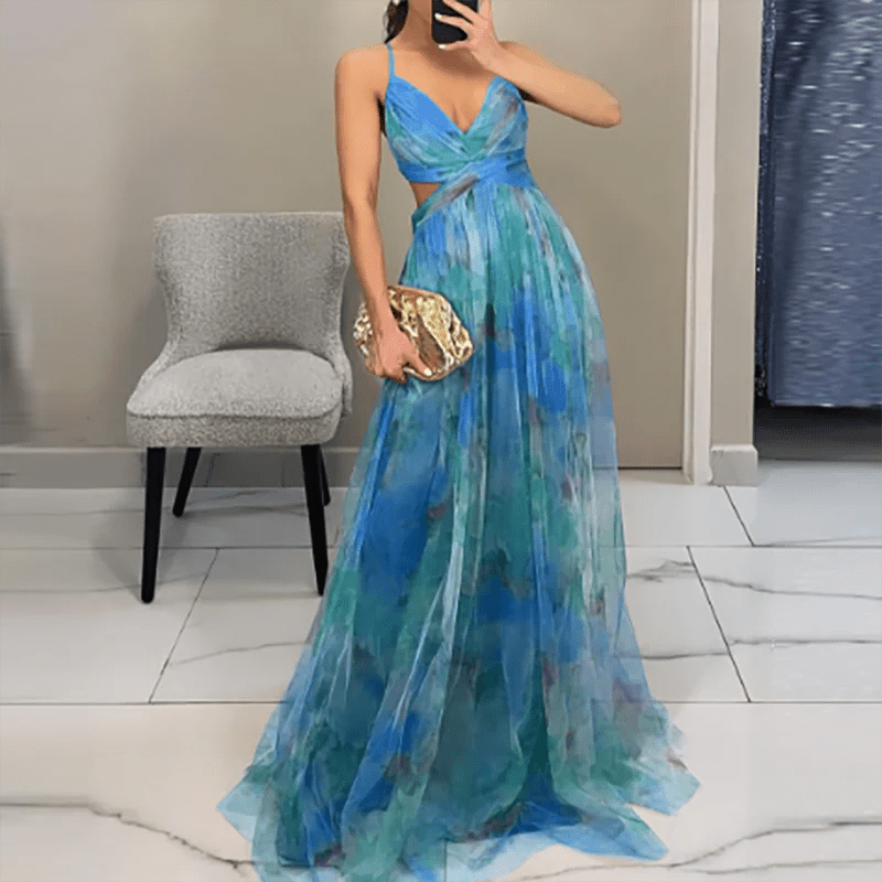 Woman wearing a blue and green evening gown holding a gold clutch in a room.