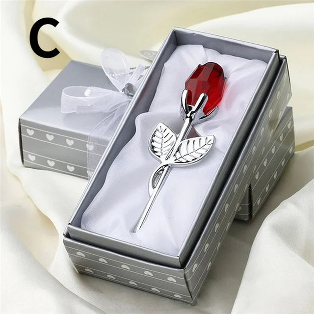 Silver rose-shaped brooch with a red gemstone in a decorative box.