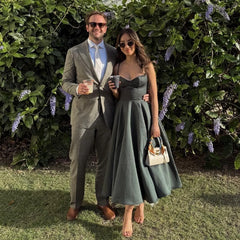 Man and woman in formal attire standing outdoors with greenery in the background