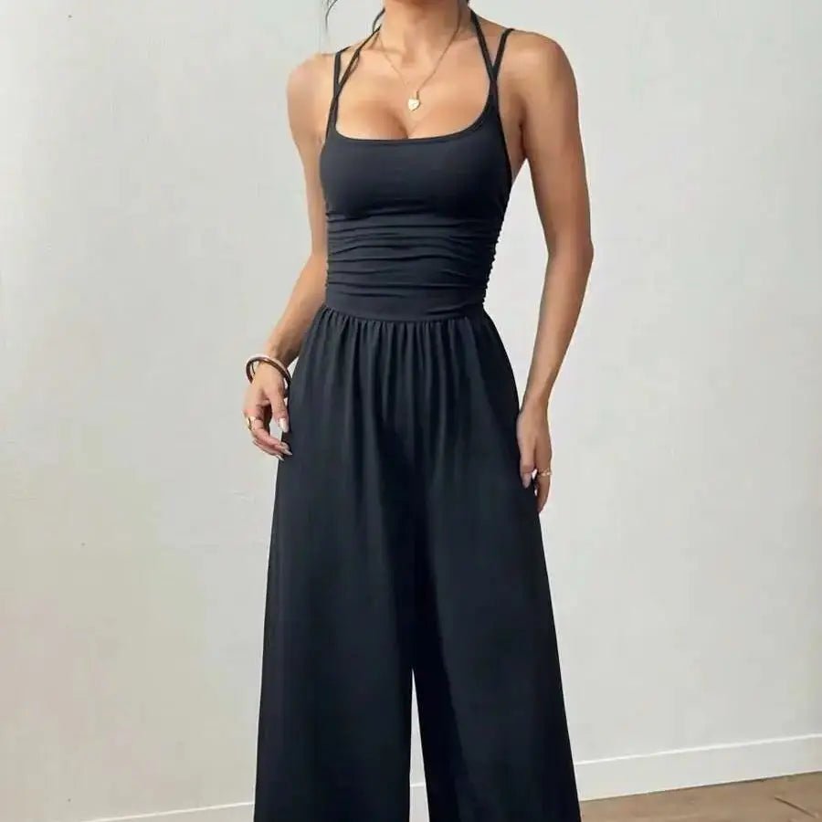 Person wearing a black sleeveless jumpsuit against a plain background