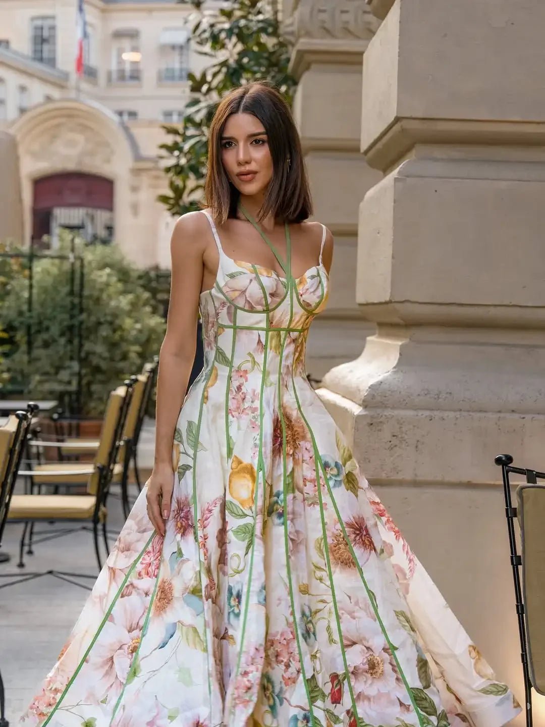 Woman in a floral dress standing outdoors near a building