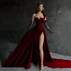 Woman in a red evening gown with a high slit standing against a dark background.