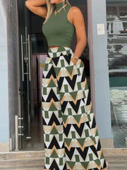Woman wearing a green sleeveless top and geometric patterned skirt standing in front of a door.