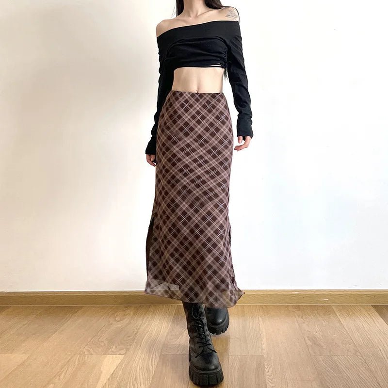 Person wearing a black off-shoulder top and plaid skirt on a plain background