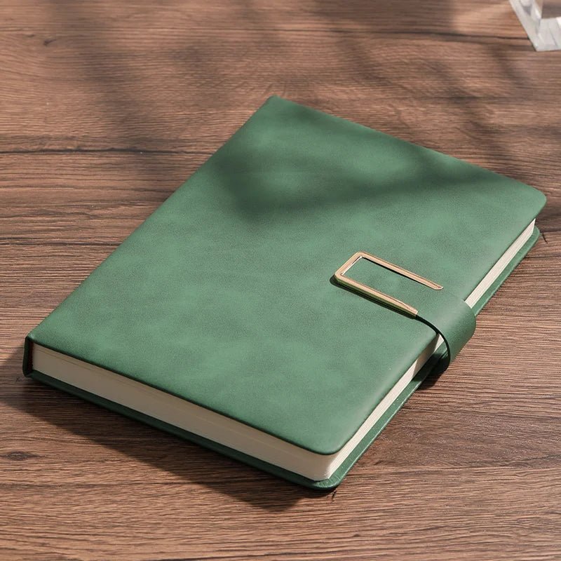 Green notebook with a gold buckle on a wooden surface