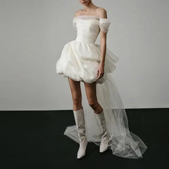 White off-shoulder dress with a tulle skirt worn by a model on a plain background