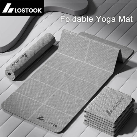 Foldable yoga mat with rolled-up mat and stacked folded mats on a wooden surface, featuring the LOSTOOK brand.