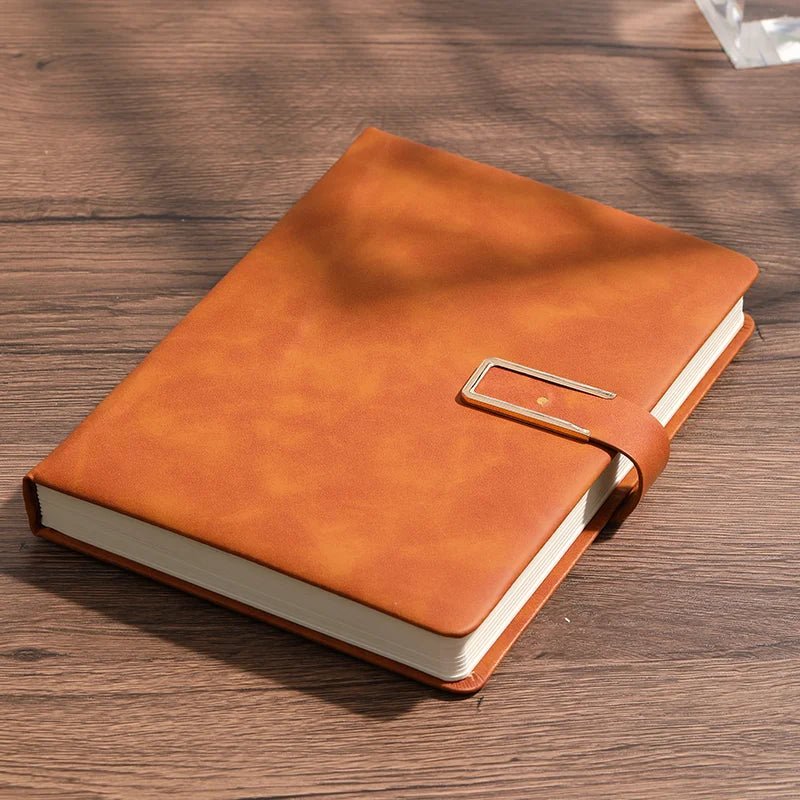 Orange leather notebook with a metal buckle on a wooden surface
