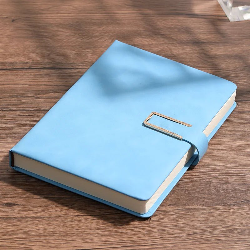 Blue notebook with a gold buckle on a wooden surface