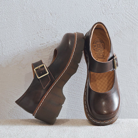 A pair of brown vintage Mary Jane shoes with buckle closure, featuring a round toe and a flat, platform sole.